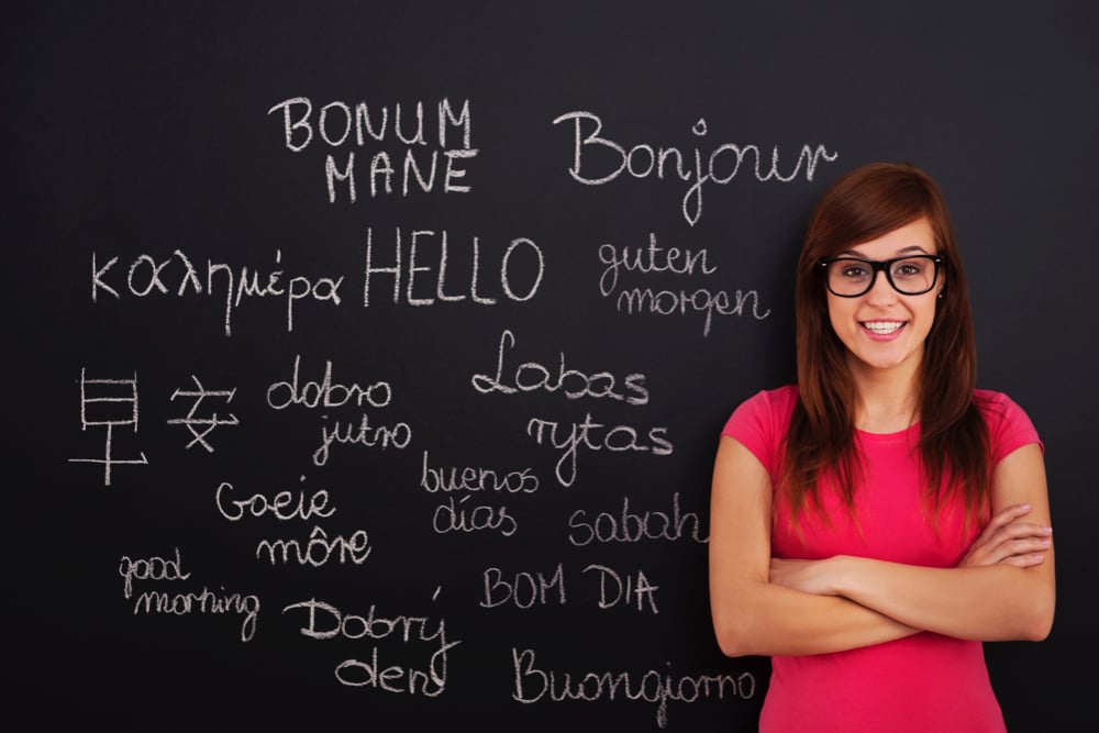 a woman, probably a teacher, in front of a blackboard in which multiple languages are wriiten. 