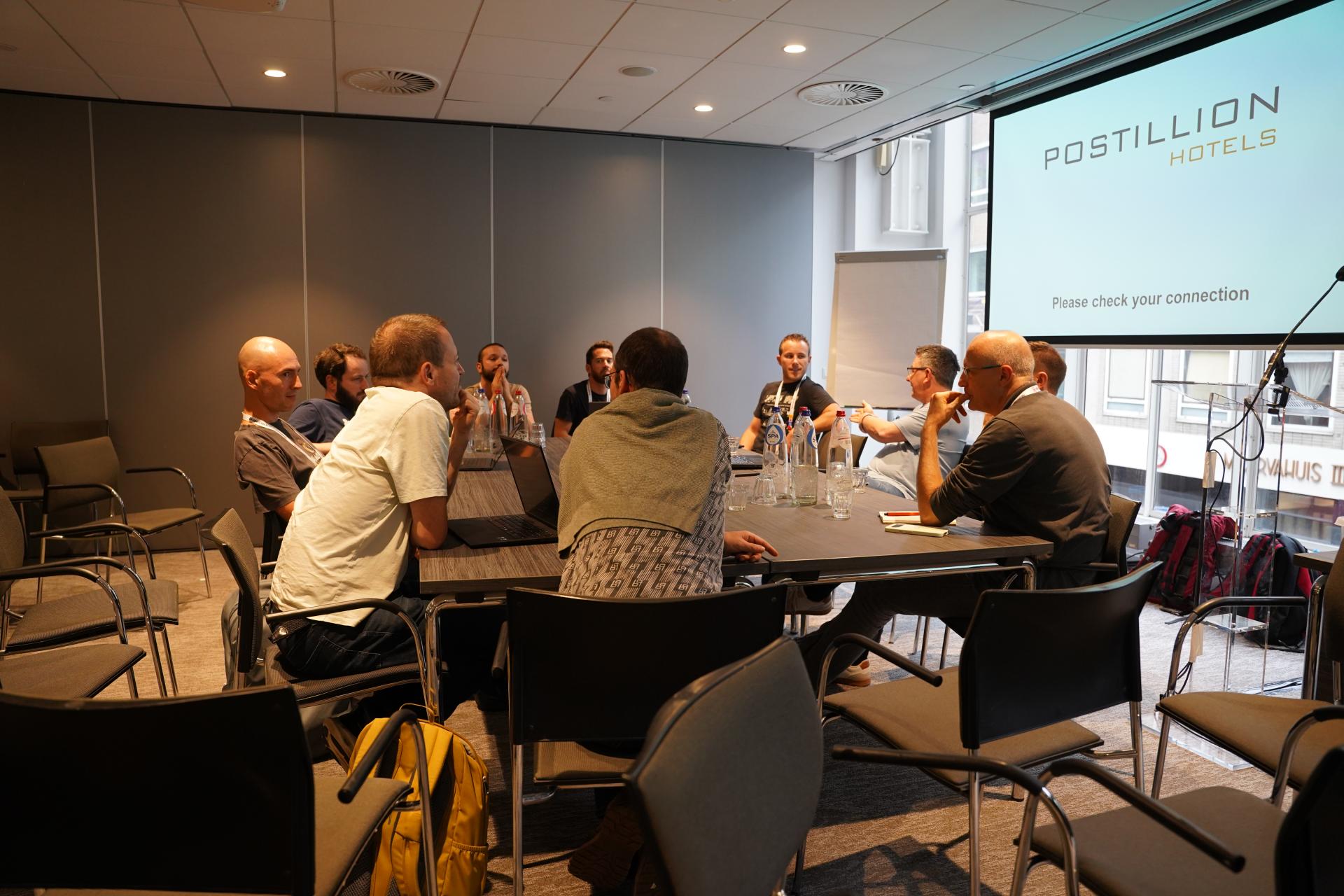 DrupalCon Rotterdam 2026 attendees seated around tables for a group discussion at Postillion Hotel & Convention Centre WTC Rotterdam.