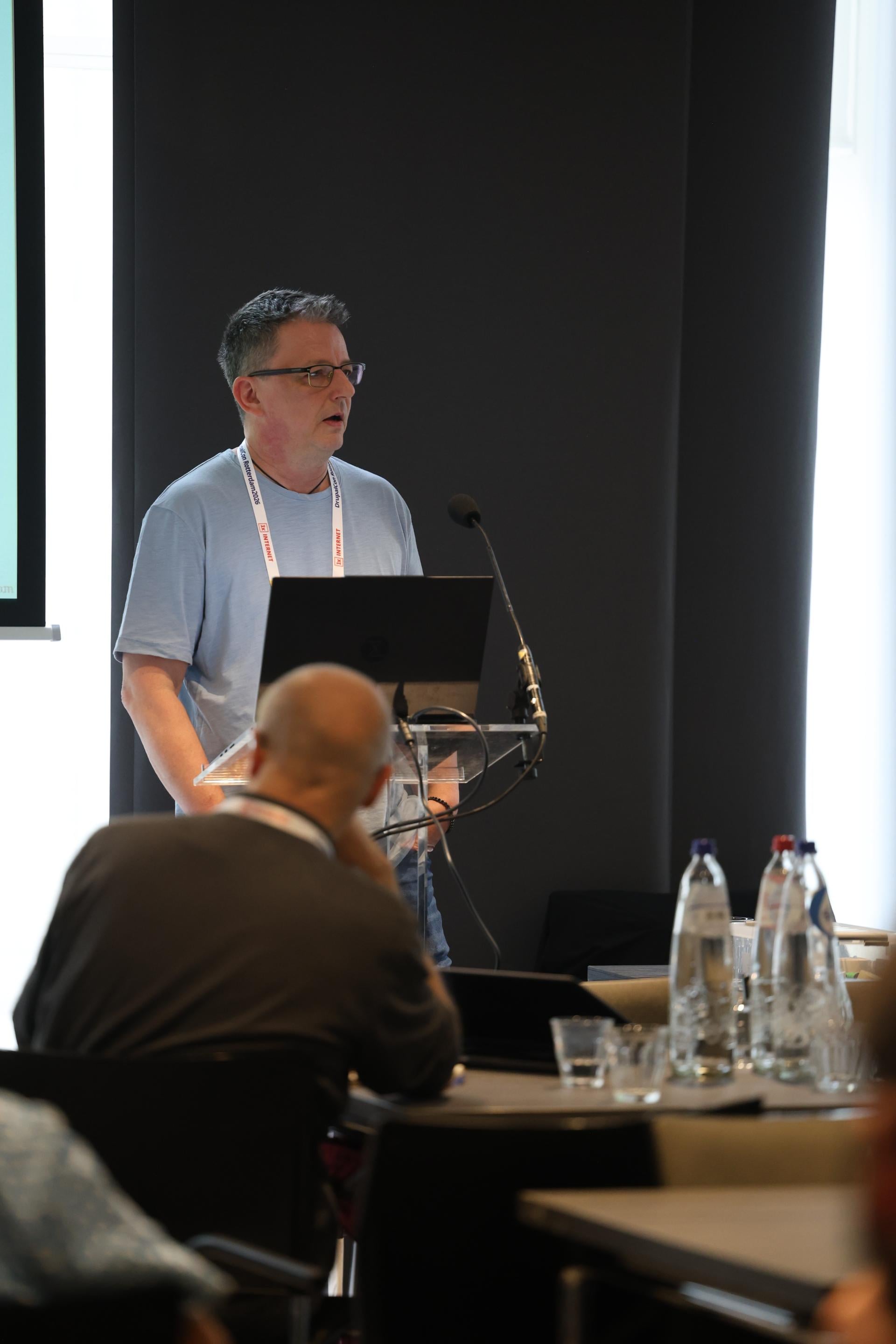 Jürgen Haas speaking at a lectern with a laptop and microphone during the AI Dev Summit in Rotterdam.