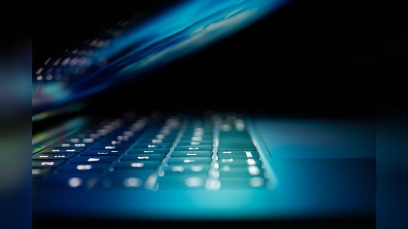 A laptop keyboard illuminated in blue light