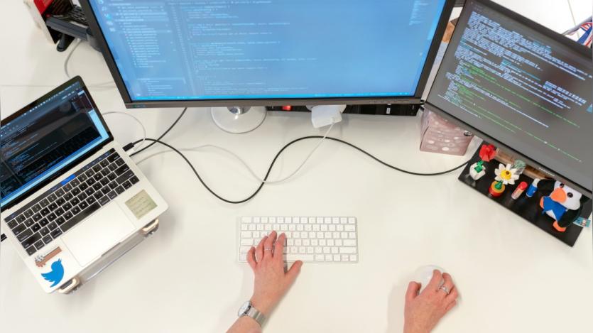  A person working on 2 systems and a laptop simultaneously