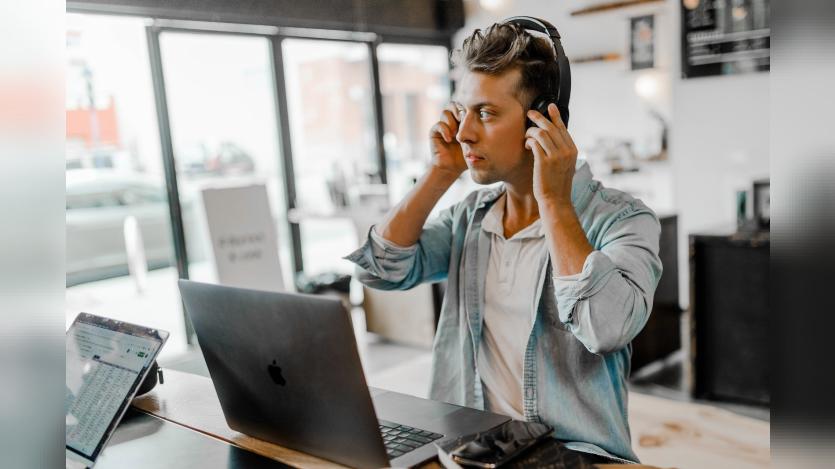 Man wearing headset infront of a silver Macbook