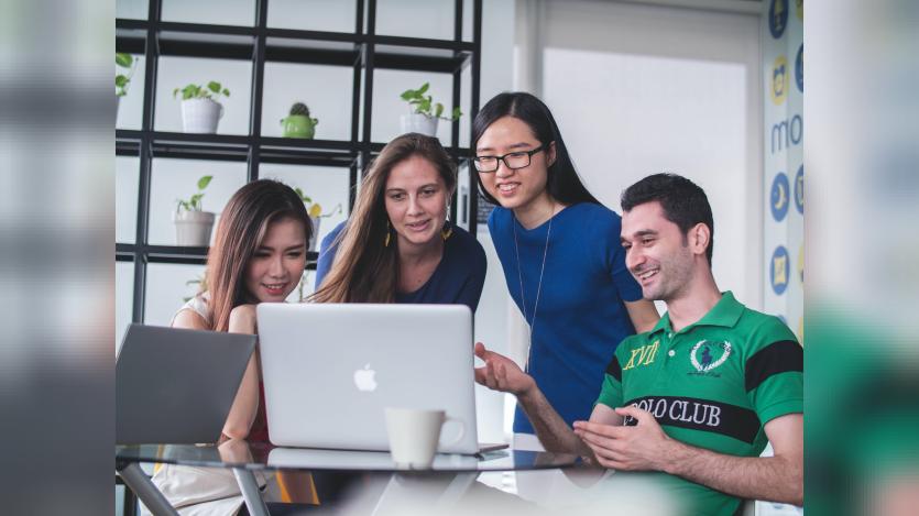 Four people looking into a laptop