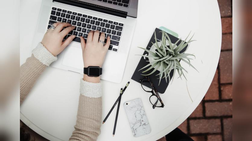 person using computer besides a plant