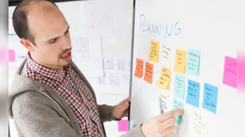 A person pasting sticky notes on a white board