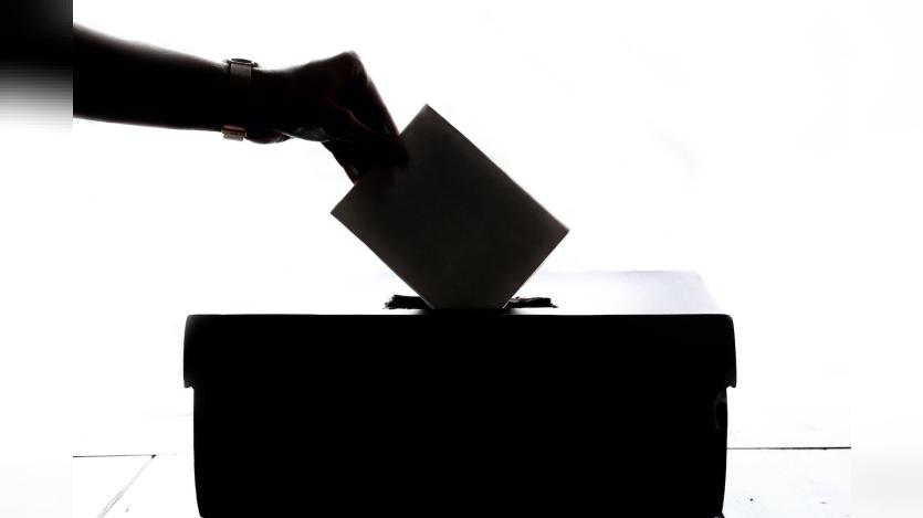 a person is casting a vote into a box