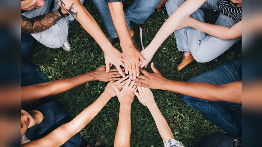 people stacking hands together in the park