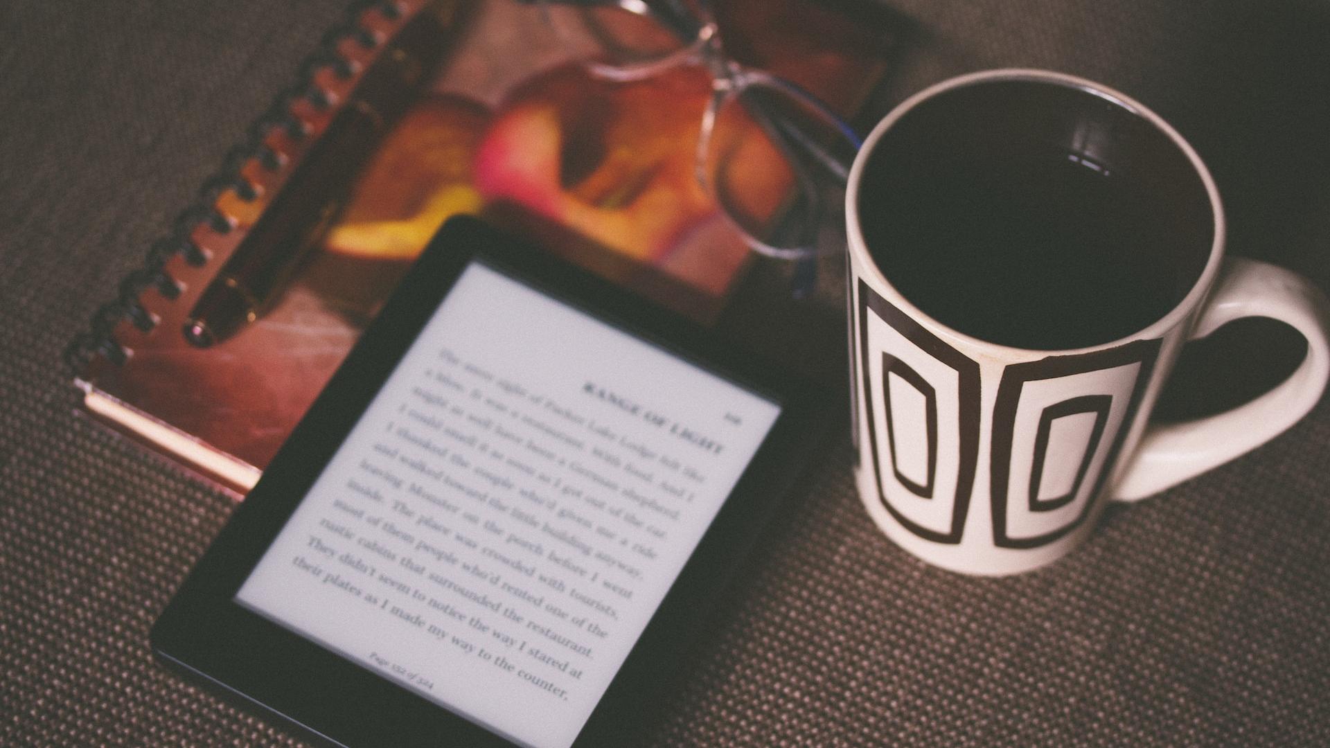 Black Kindle on a book and near a mug