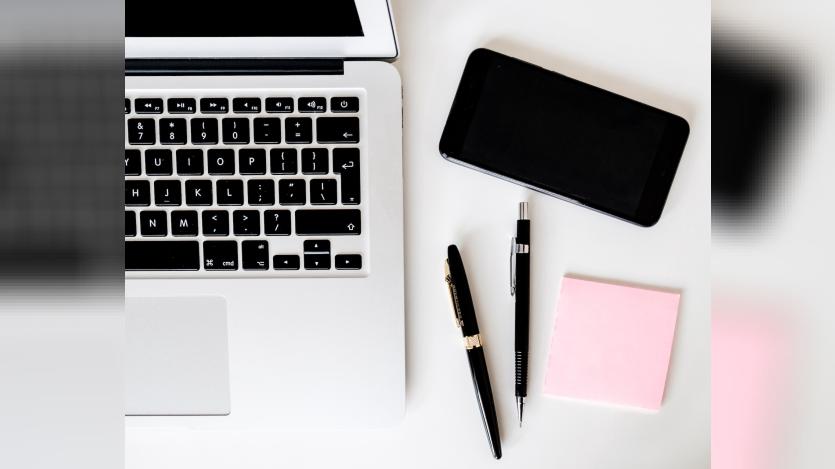 a silver Mac, an iphone, 2 pens