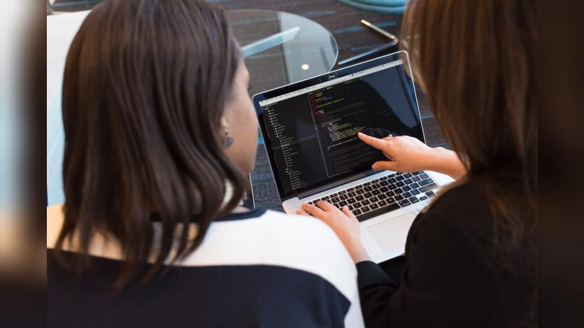 Two women discussing pointing at a laptop