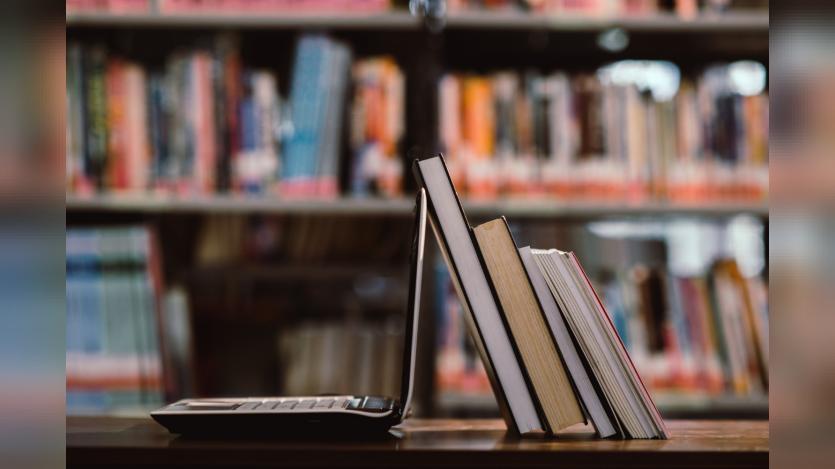 laptop computer and book on workplace in library room