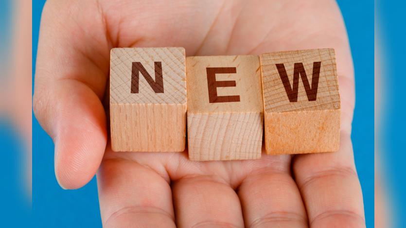 hand holding wooden cubes with word new.
