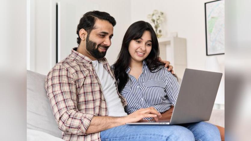 husband and wife on couch going through laptop