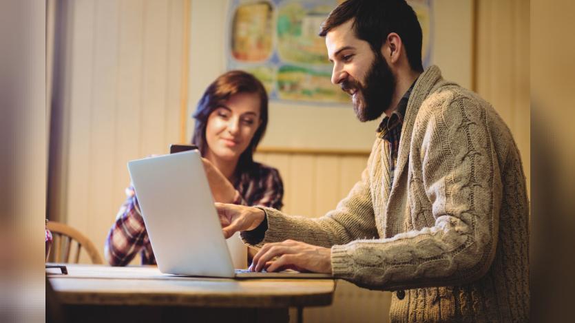 Couple interacting while using laptop and mobile phone