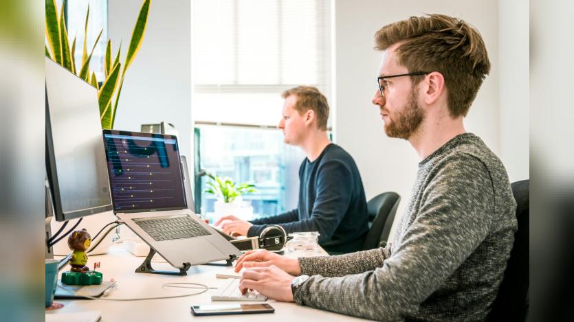 man-sitting-on-chair-wearing-gray-crew-neck-long-sleeved-shirt-using-apple-magic-keyboard