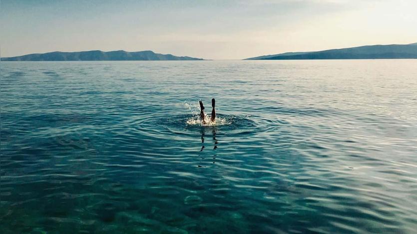 A person diving into ocean with legs up