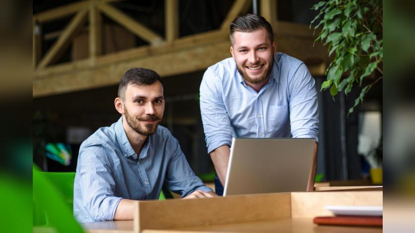 Picture of handsome businessman listening to his colleague or partner concerning ner business system while working on laptop computer in office interior