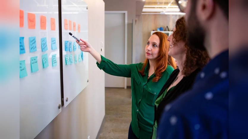 person pointing at sticky notes at board