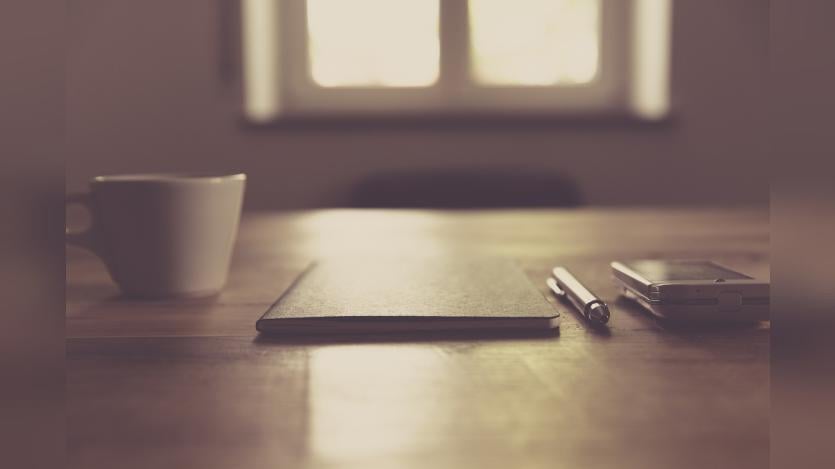 A coffee cup, diary, pen and mobile phone on a table