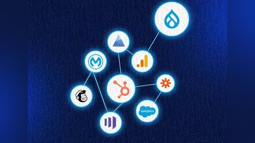 Network diagram featuring the HubSpot sprocket logo at center connected by lines to service icons for Drupal (water droplet), Google Analytics (bar chart), Zapier (asterisk), Salesforce (cloud), Mailchimp (chimp face), Mautic (stylized “M”), Microsoft Azure (triangle), and a three-bar metrics logo.