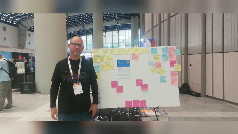 Michael Lenahan standing beside the DrupalCon Rotterdam Jobs Board, covered with handwritten vacancy and job-seeker cards at the conference venue.