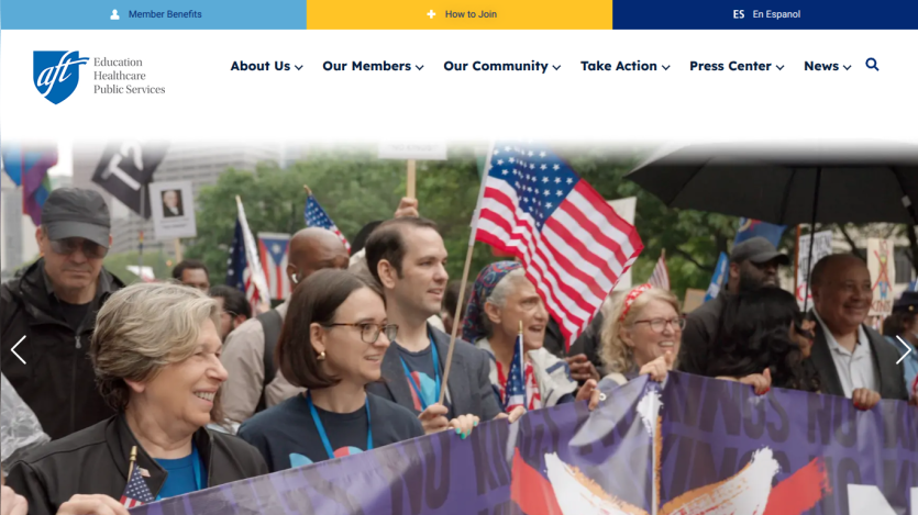 A diverse group of people holding a banner and flags at a public event, with a clear header above.
