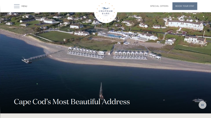 Aerial view of a beach resort with text 'Cape Cod's Most Beautiful Address' and navigation menu with booking option