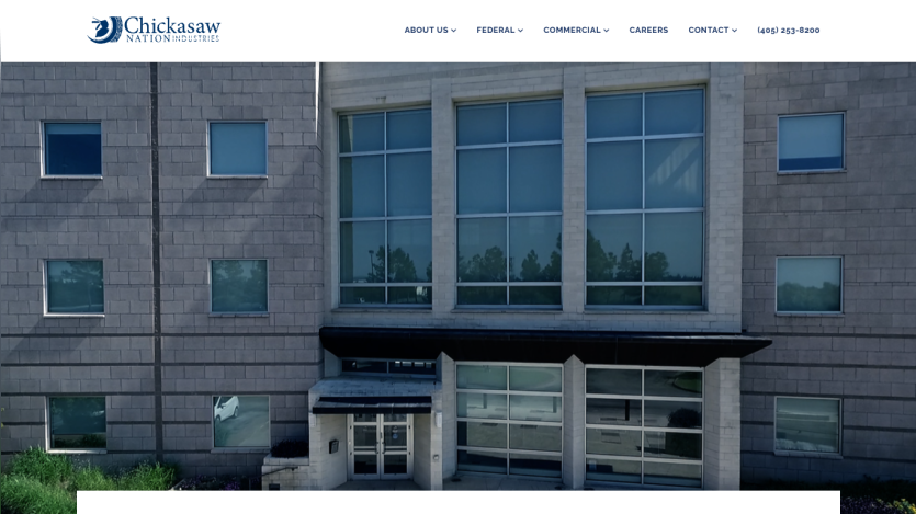 Chickasaw Nation Industries website header with navigation and a building facade in the hero section