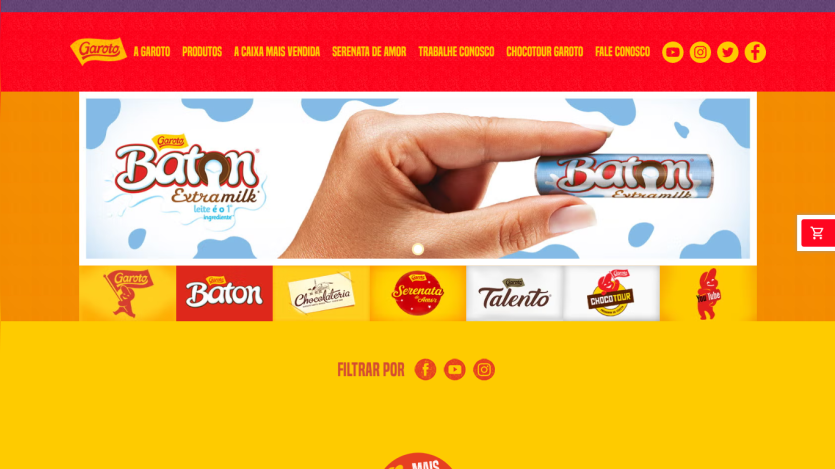 Garoto website header with navigation and hero section featuring Baton Extramilk chocolate product held by hand.