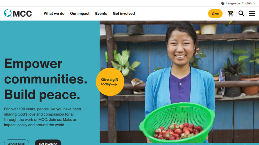 Nonprofit site hero with headline empowering communities and building peace, call to action buttons, and smiling woman holding strawberries