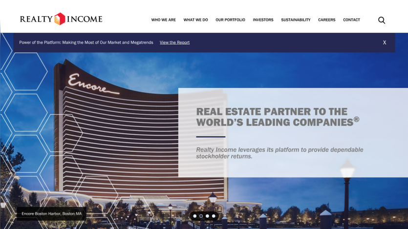 Realty Income homepage featuring a large warehouse image and text about being a real estate partner to leading companies