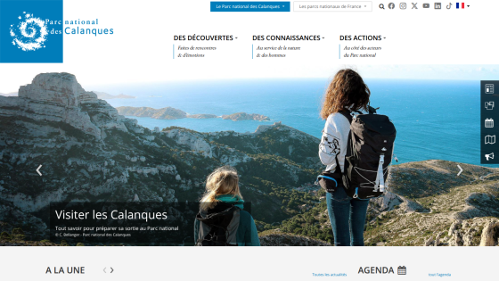 National park website with navigation and hero image showing two hikers overlooking coastal cliffs and sea