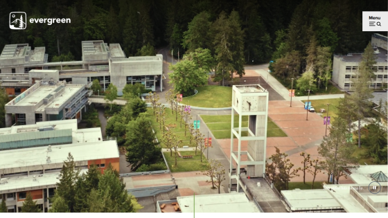 Aerial view of a college campus with buildings and a clock tower in a green setting.