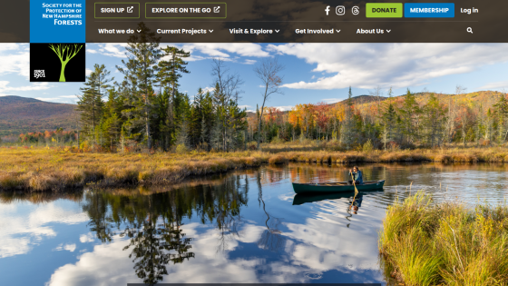 Society for the Protection of New Hampshire Forests website with navigation and a hero image of a person canoeing on a reflective lake surrounded by autumn trees