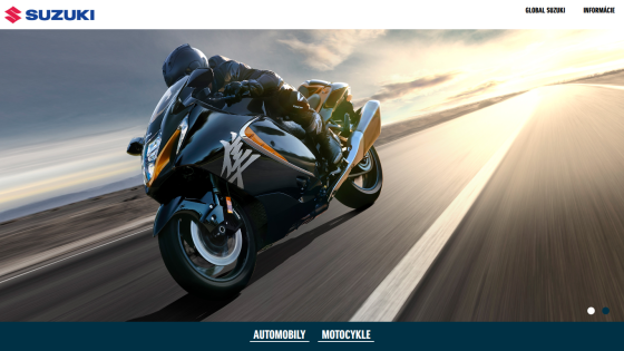 Suzuki website hero with a motorcyclist riding a black Suzuki motorcycle on a road at sunset, navigation links for Automobily and Motocykle
