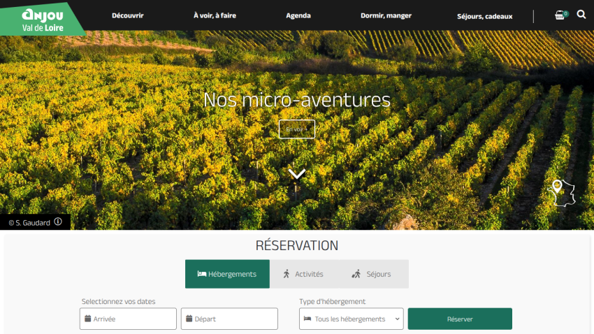 Travel website featuring vineyard hero image with 'Nos micro-aventures' and reservation options for accommodations, activities, and stays