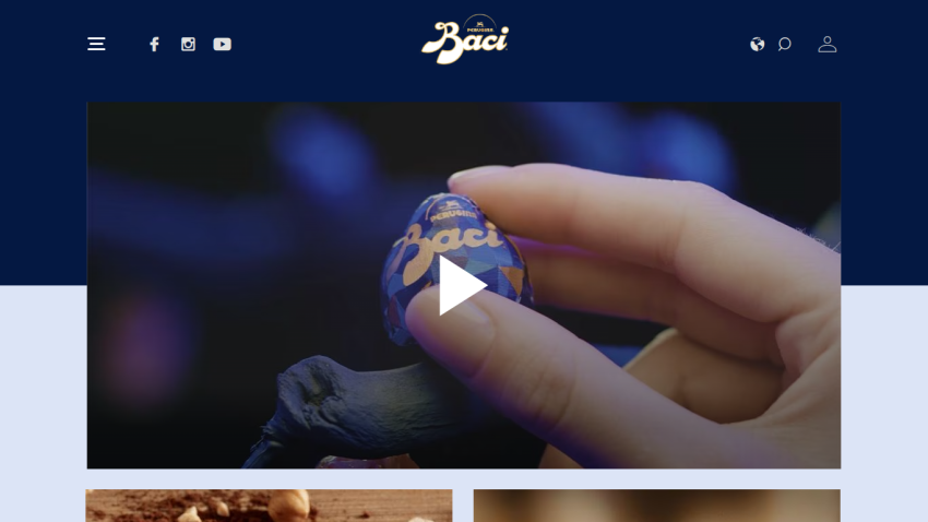 Baci Perugina website header with navigation and a hand holding a Baci chocolate in a video player