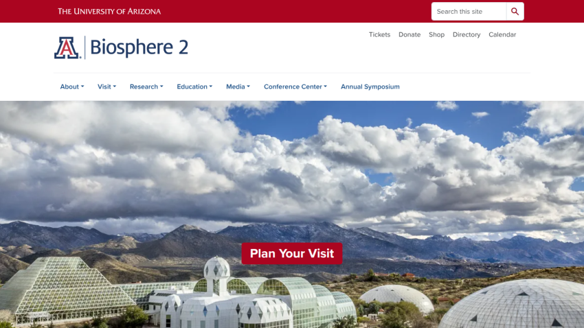 University of Arizona Biosphere 2 website with navigation and a large hero image of Biosphere 2 domes and mountains under a cloudy sky