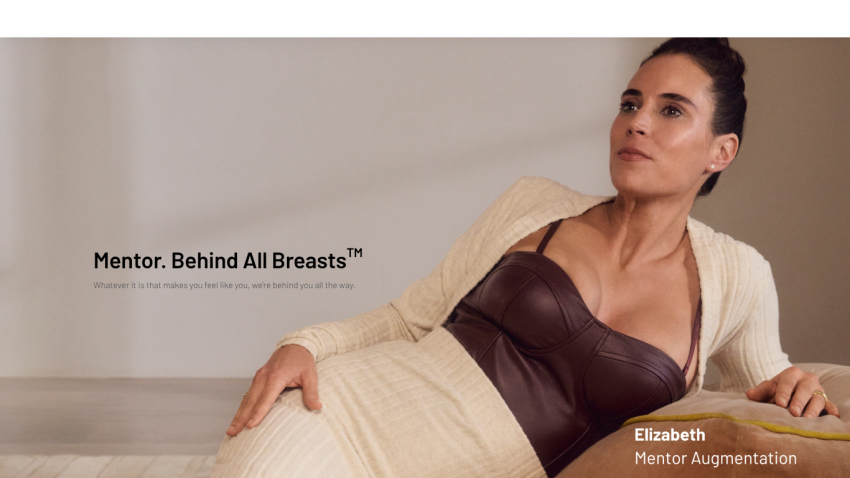 Mentor breast augmentation brand with tagline 'Mentor. Behind All Breasts' and a woman reclining in a leather bustier and cardigan