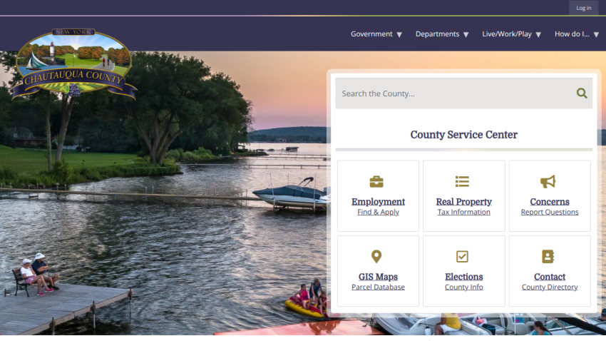 Chautauqua County New York website with navigation menu, search bar, and county service center options over a lakeside sunset background