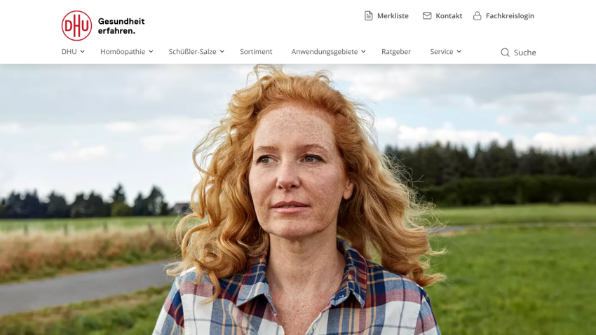 Website header with navigation menu and a hero image of a woman with red hair outdoors in a field
