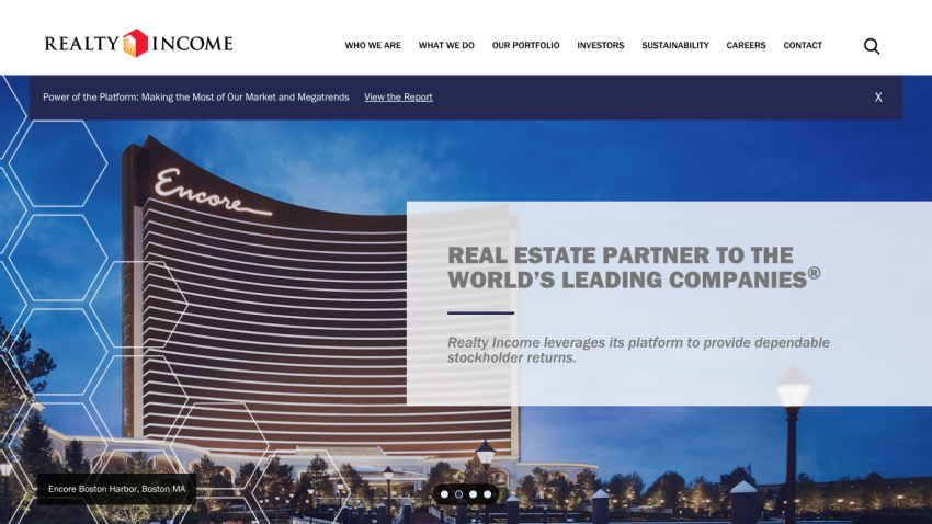Realty Income homepage featuring a large warehouse image and text about being a real estate partner to leading companies