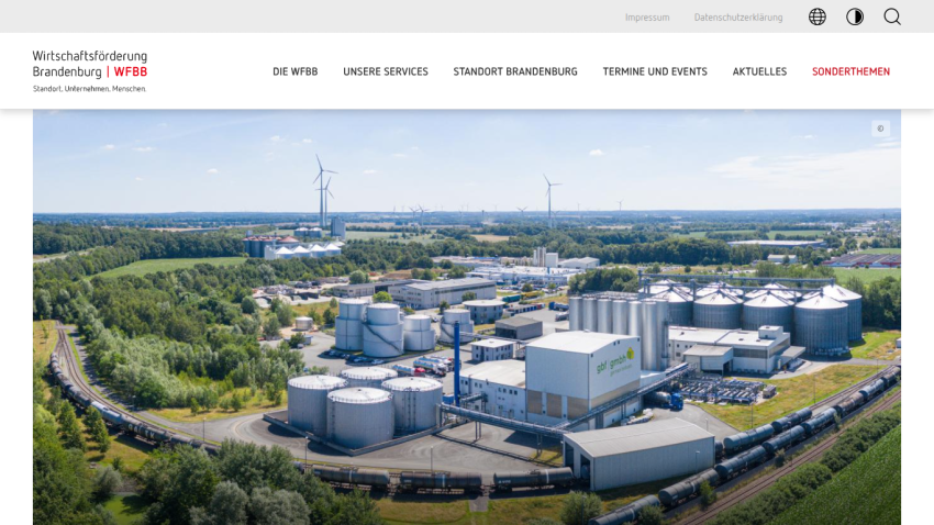 Economic development site in Brandenburg with industrial buildings, wind turbines, and train tracks
