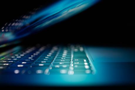 A laptop keyboard illuminated in blue light
