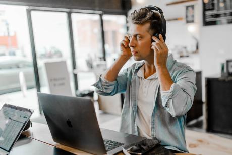 Man wearing headset infront of a silver Macbook