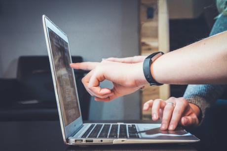 A man points finger at a laptop screen