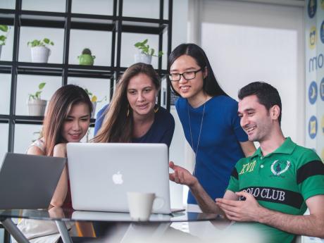 Four people looking into a laptop