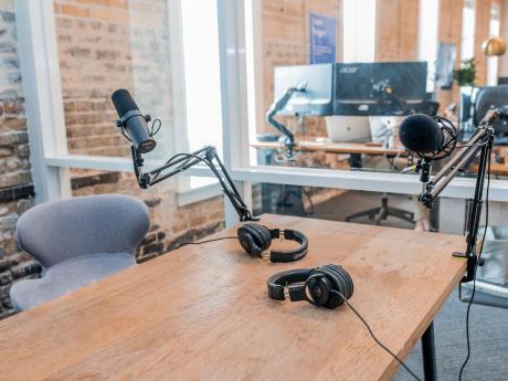 two microphones and two black headphones on a wooden table