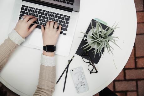 person using computer besides a plant