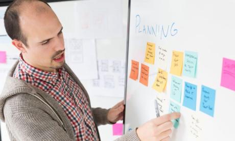 A person pasting sticky notes on a white board